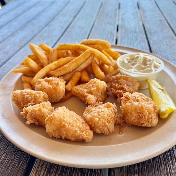 Fried shrimp and french fries with tartar sauce and a lemon wedge on a plate.